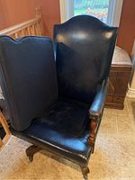 Front view of the vintage executive office chair with removable cushion placed on tiled floor. Shows curved backrest and matching dark blue cushion adjacent.