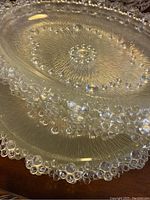 Close-up photo showing the beaded glass edge detail and textured glass surface of a round serving plate.