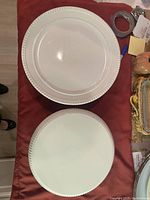 Top view of two white porcelain pedestal cake plates showing one has a scalloped, textured rim, the other with a smooth rim.