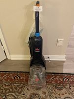 Full view of Bissell ReadyClean PowerBrush carpet cleaner showing upright design, transparent base, and power cord.