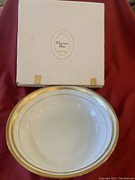 Top view of the white vegetable bowl with two gold rings near the rim and the original Christian Dior box behind it.