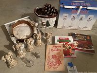 Wide view showing porcelain angel bells, leather jinglebell strap, holiday basket with pinecones, cookbooks, boxed goblets, and small bells.