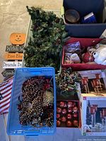 Top view of multiple bins containing holiday decorations, garland, teddy bears, decorative picks, and a Halloween sign visible next to bins.