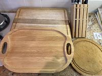 Wooden cutting boards and cutlery block arranged on kitchen counter, showing three wood cutting boards and a cutlery block with knives