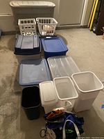 Full assortment of plastic bins, trash cans, laundry basket, and bags arranged for lot overview.