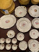 Full set of Theodore Haviland Breton china pieces arranged, showing plates, bowls, cups, saucers, sugar bowl, serving platter, casserole with handles and floral/gold detail.