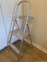 Side front angle view of Werner aluminum step ladder showing overall frame, steps and safety rail.