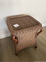 Front and side angled view showing woven wicker texture and wooden handles on the side.