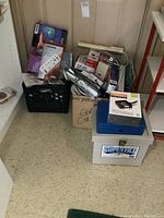 Photo showing crates, boxes, and a SuperFile storage box with assorted computer accessories and power cords stacked around.