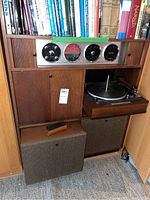 Front view of open cabinet showing Electrohome stereo system gauges, turntable on sliding shelf, and two external speaker boxes at the bottom.