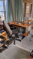 Full view of office desk with attached small side shelf and gray office chair in front. Items on desk surface not included.
