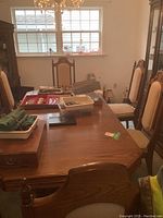 Full view of dining table and chairs showing oak finish, rectangular shape with leaf, and beige upholstered chairs.