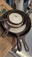 Stack of five cast iron frying pans showing top view with handles