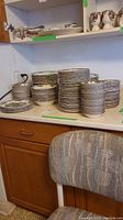 Wide view of stacked plates on countertop with mugs on shelf