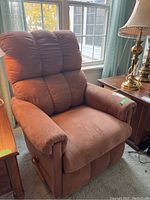 Brown La-Z-Boy recliner chair with cushioned back, seat and padded armrests in front of window with natural light.