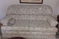 Front view showing floral pattern and overall condition of love seat. Extra fabric visible on seat cushion.