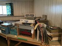 Overall view of table with mixed model train boxes, loose caboose in display case and prints leaning