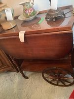 Full side view of the wooden tea wagon with glass tray on top and wooden wheels.