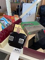 View-Master viewer with light attachment box and several slides in a red slide holder