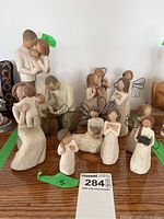 Wide view of twelve Willow Tree figures, including family and angels, showing varied sizes and some figures holding children.