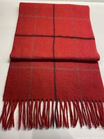 Full view of the coral lambswool scarf with grey and black check pattern, folded with fringed ends clearly visible.