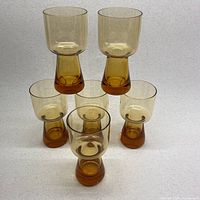 Full set of 6 amber glass cups arranged in a pyramid shape viewed from the front