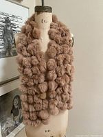 Front view of the dyed rabbit fur scarf displayed on a mannequin, showing the plush fur balls and tubular lacing design.