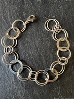 Sterling silver bracelet laid out flat showing alternating large flat loops and pairs of smaller rounded loops with lobster clasp.
