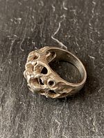 Angle view of vintage sterling silver ring showing textured bubbly, rocky surface with openwork