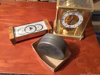 Piston fragment, Atmos clock, weather gauge displayed on wooden surface