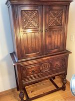 Full frontal view of entire hutch showing two-section design, carved doors, lower drawer and base with legs and stretcher