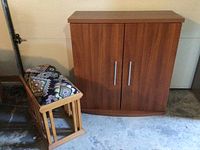 Laminate cabinet and upholstered footstool shown side by side, cabinet front view closed, footstool angled with geometric pattern visible