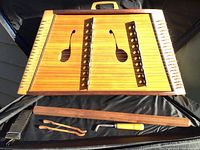 Top-down view of harp laid flat with bridges, strap, picks, and wrench