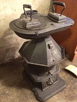 Full view of octagonal cast iron stove standing approx. 26 inches tall with two flat irons on top