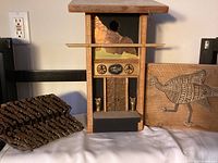 Birdhouse flanked by carved panels and metal basket on shelf