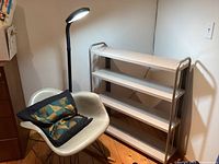 Overall view showing rocking chair with pillow, white metal shelf, and black floor lamp