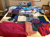 View of miscellaneous fabrics of various colors and patterns spread out on a table.