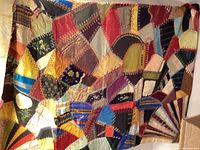 Vintage crazy quilt with many fabric types and hand stitching in varied warm colors