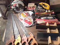 Full view of the saw collection on a wooden table including Skilsaw circular saw, hand saws, blades, and DeWalt jigsaw.
