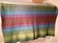 Green, blue and pink horizontal striped wool blanket draped over rod