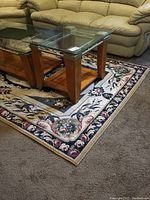 Area rug under glass coffee table and brown couch, showing full rug design and scale.