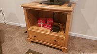 Front view of wooden TV stand showing open shelf with objects and drawer below