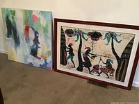 Side by side photo of two wall art pieces: one framed batik style artwork with wood frame, and one unframed abstract canvas painting