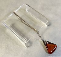 Full view of the pendant on the silver chain displayed on an acrylic stand