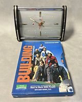 Front view of the mechanical alarm clock and the 5-CD Building Relationships set in its case