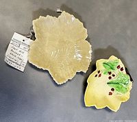 Top view of two leaf-shaped dishes: off-white Belleek porcelain dish and hand-painted Carlton Ware dish with berry decoration