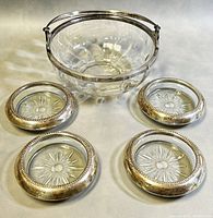 The full lot showing the antique Cristofle signed crystal bowl with silver plated handle and rim, alongside the four sterling silver rimmed crystal ashtrays arranged around the bowl.