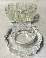 Photo showing two different textured clear glass ashtrays stacked together to show form and texture.