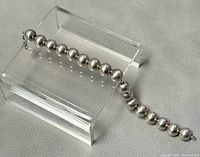 Full view of 925 silver beaded ball bracelet displayed on a clear stand, showing spherical silver beads connected in sequence.