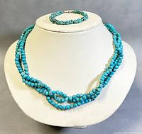 Turquoise beaded necklace and bracelet displayed on jewelry stand showing full necklace and bracelet.